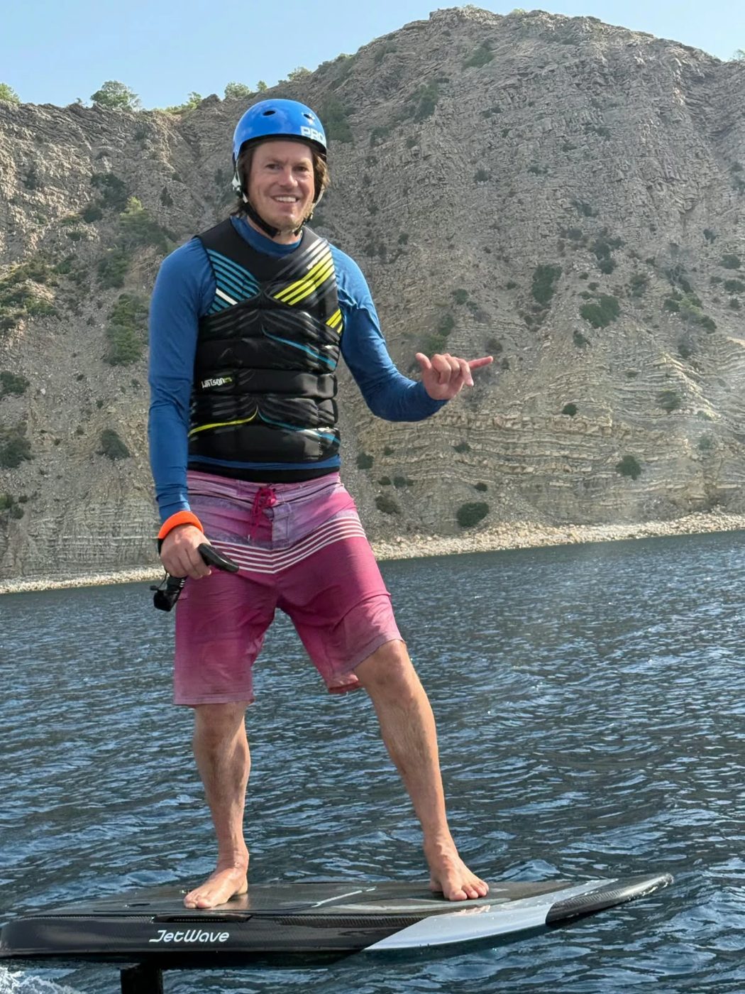 Jan Willem staat lachend op een JetWave eFoil-board voor de kliffen van Ibiza