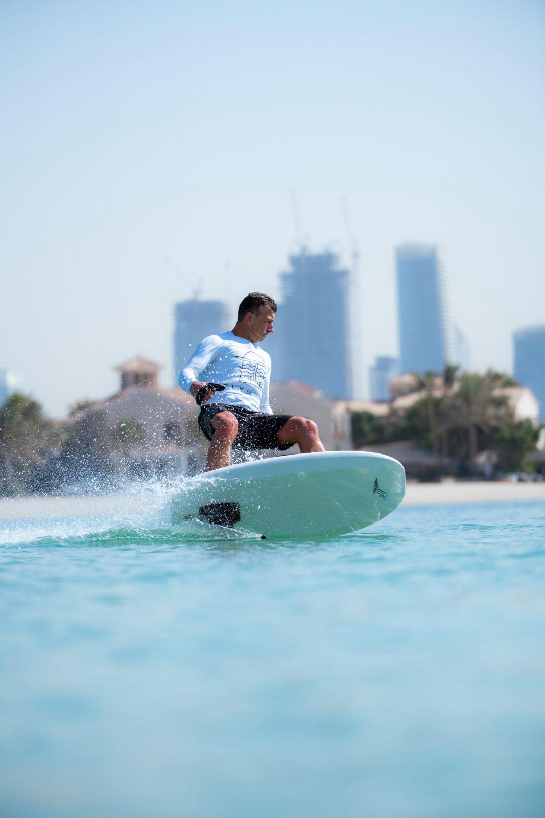 Piet Varkevisser vaart laag over turquoise water met hoge torens op de achtergrond