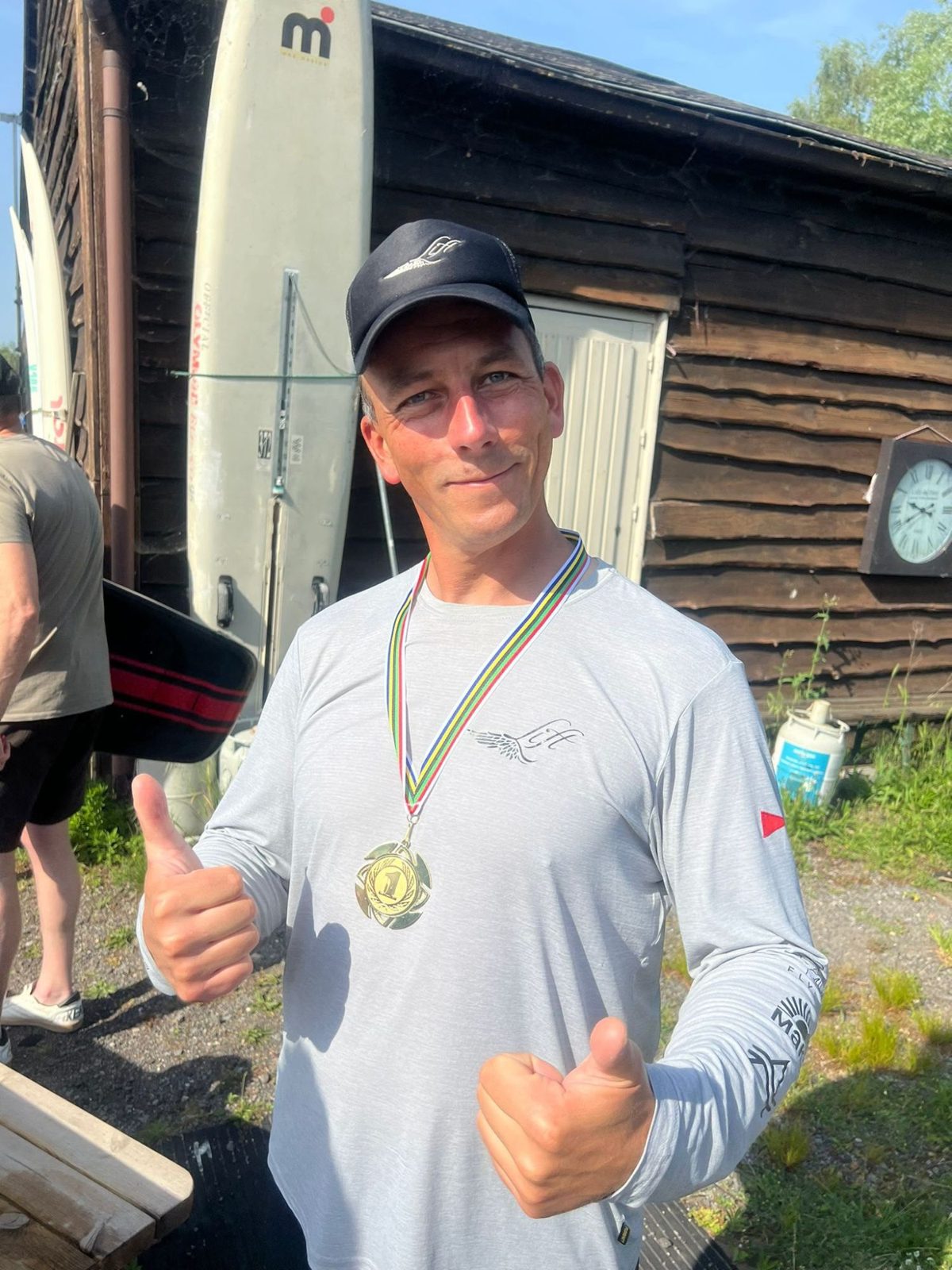 Piet Varkevisser met een gouden medaille om zijn nek steekt twee duimen op