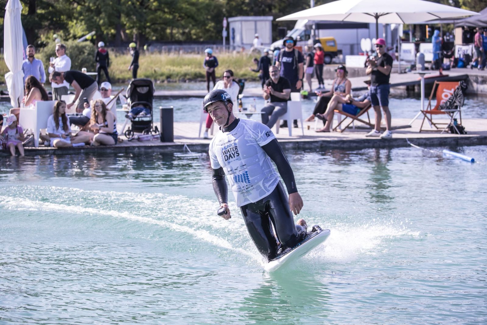 Piet Varkevisser vaart op zijn knieën op een eFoil langs een volle kade tijdens de SFT eFoil World Cup in München